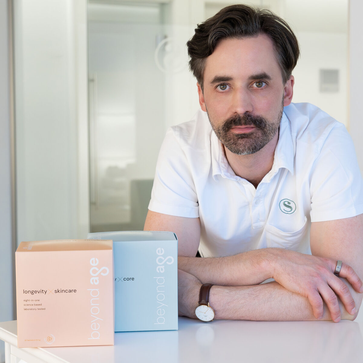 Foto von Dr. med. Philippe Snozzi mit den Longevity-Produkten von Beyond Age auf der linken Seite von seinen Armen